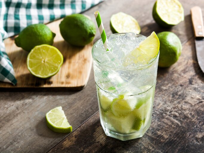 Ein Glas gefüllt mit selbst gemachtem Caipirinha - daneben die passenden Zutaten. | © iStock/etorres69