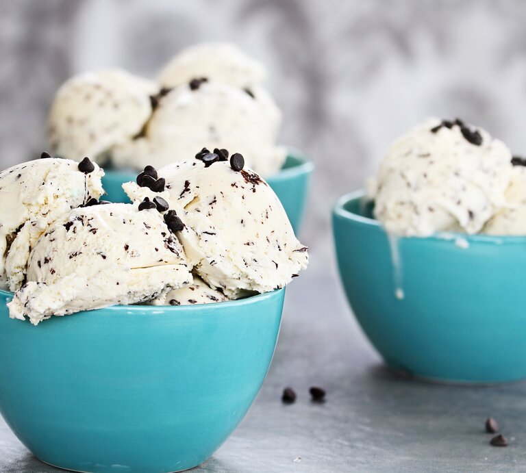 Hellblaue Schalen mit dem Straciatella-Eis auf hellem Holzuntergrund. | © istock/StephanieFrey