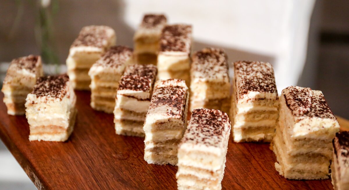 Cremiger, geschichteter Kuchen auf Holzbrett. 