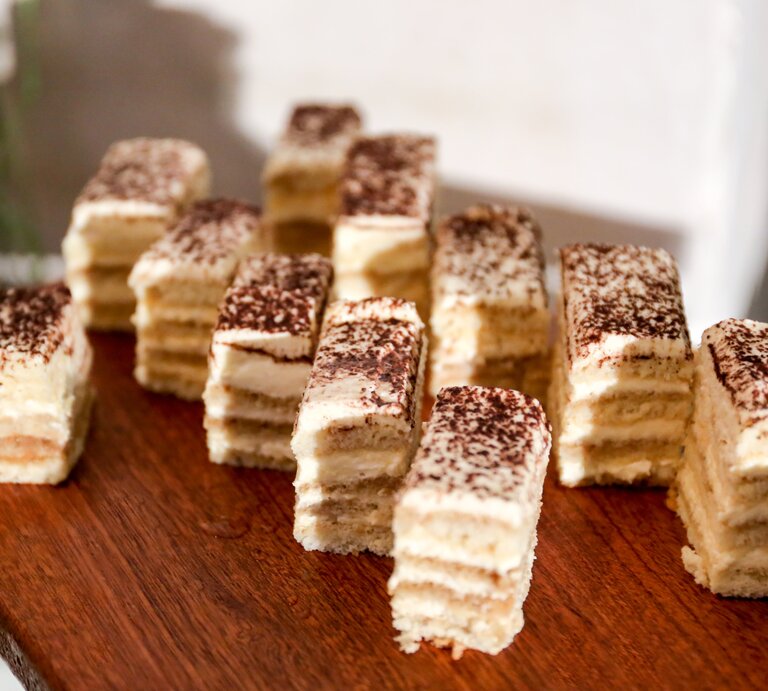 Cremiger, geschichteter Kuchen auf Holzbrett.  | © GettyImages/JunzPortraits