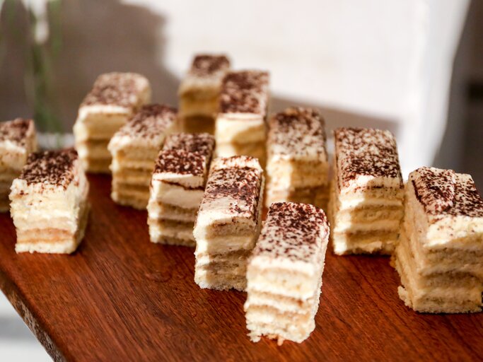 Cremiger, geschichteter Kuchen auf Holzbrett.  | © GettyImages/JunzPortraits