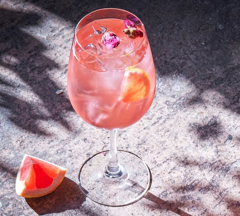 Ein Glas Pink Spritz auf ein er Betonfläche von schräg oben fotografiert. | © Shutterstock/ Sasha_P