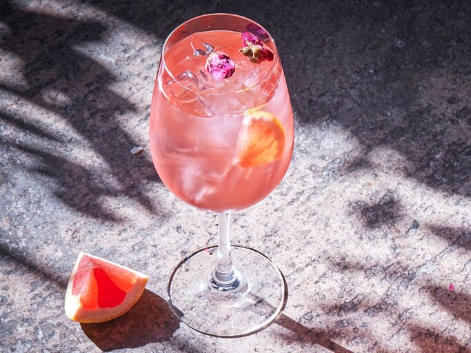 Ein Glas Pink Spritz auf ein er Betonfläche von schräg oben fotografiert. | © Shutterstock/ Sasha_P