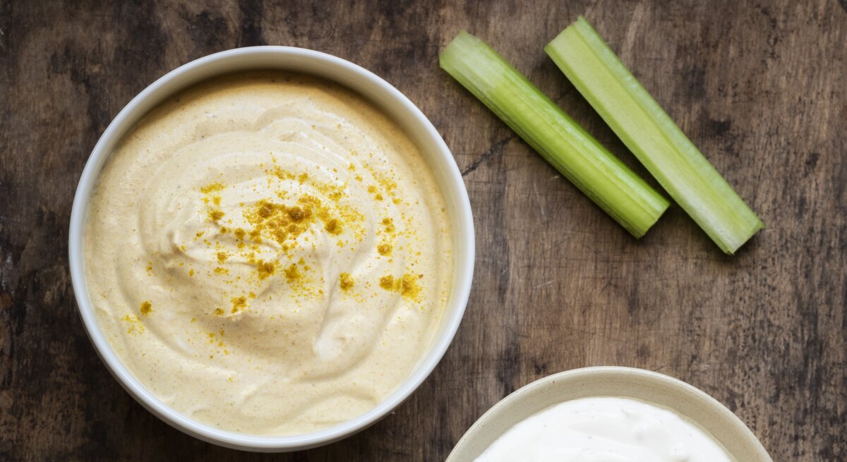 Curry-Dip mit Rohkost auf hölzernem Untergrund.
