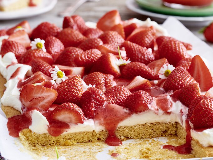 Der angeschnittene Erdbeer-Kuchen in der Nahaufnahmen mit Frühlingsblumen.  | © EAT CLUB/ Isabell Triemer