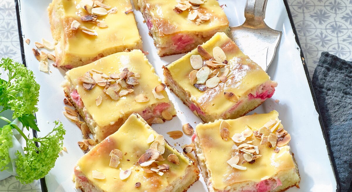 Rhabarber-Mandelkuchen mit Eierlikör in einer weißen Backform auf grauem Hintergrund. 