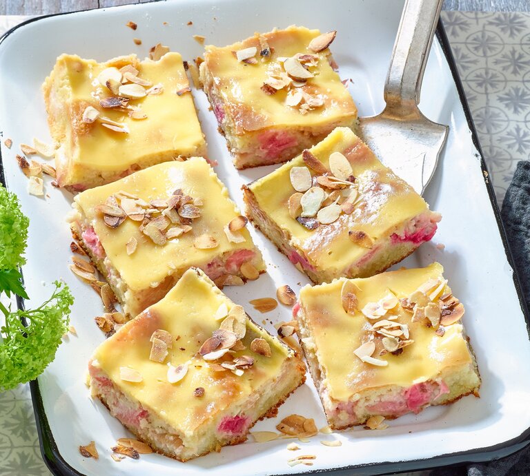 Rhabarber-Mandelkuchen mit Eierlikör in einer weißen Backform auf grauem Hintergrund.  | © Matthias Liebich