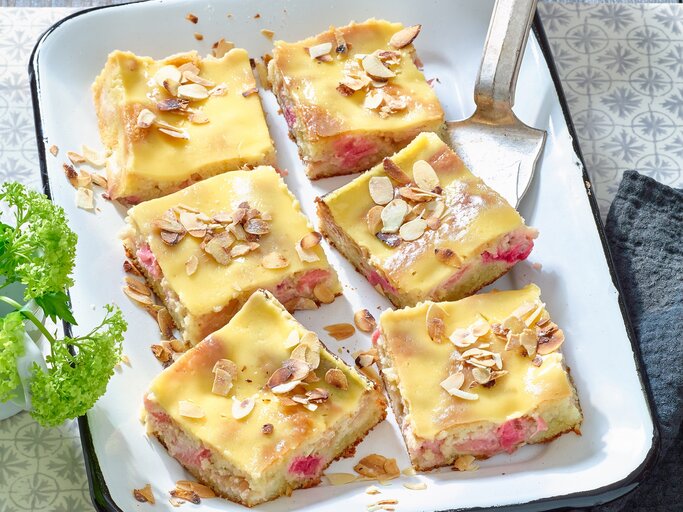 Rhabarber-Mandelkuchen mit Eierlikör in einer weißen Backform auf grauem Hintergrund.  | © Matthias Liebich