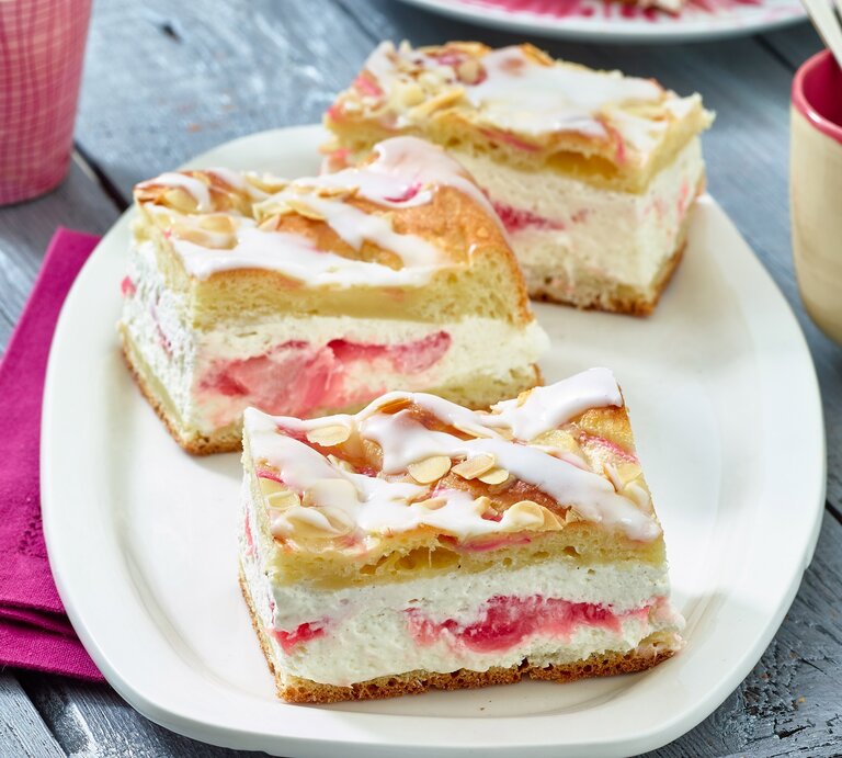 Auf einem ovalen hellen Teller aus Porzellan sind drei Stücke Rhabarber-Kuchen | © Matthias Liebich