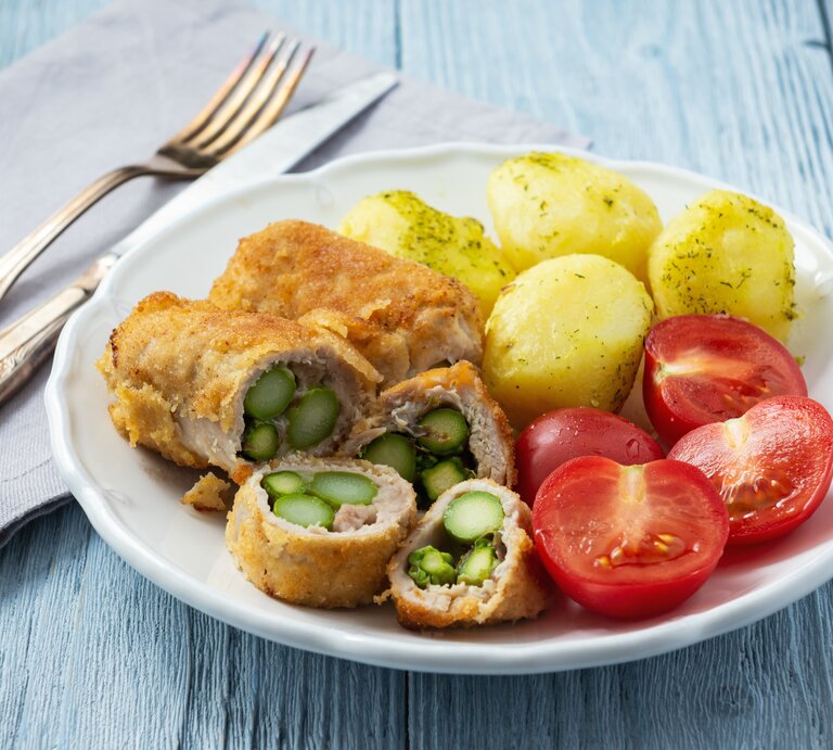 Schnitzel gefüllt mit Spargel zu Dill-Kartoffeln und Tomaten auf weißem Teller.  | © Getty Images/ Oleg Bannikov