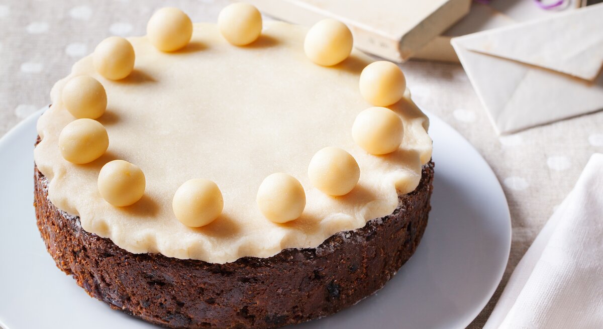 Runder Kuchen mit einer Marzipanschicht und runden Marzipan-Kugeln belegt. 