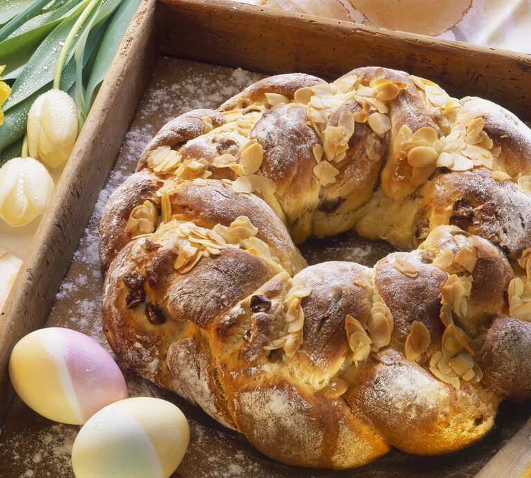 Der Osterkranz auf einem Holzbrett mit Oster-Deko im Hintergrund. | © StockFood / Harry Bischof