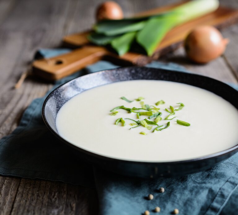 Ein schwarzer Suppenteller gefüllt mit einer cremigen, pürierten Lauchsuppe.  | © iStock.com/NoirChocolate