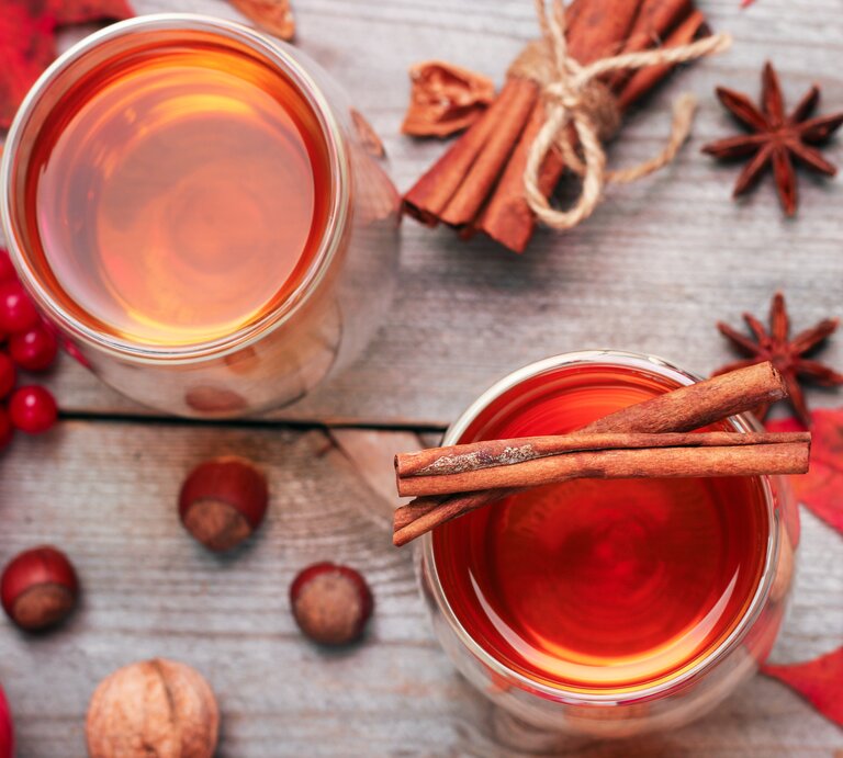 Rosé-Glühwein von oben, umrundet von weihnachtlichen Gewürzen und roter Deko.  | © Shutterstock/Antonina Vlasova