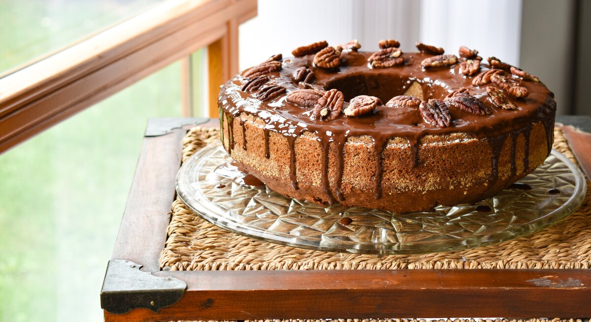 seitliche Ansicht auf einen runden Kuchen mit Glasur und Nüssen. 