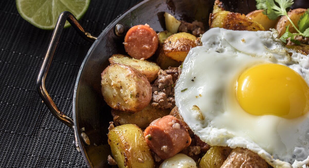 Deftige Kartoffelpfanne mit Würstchen und Hack garniert mit Spiegelei. 