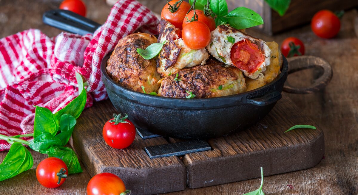  Hühnerhackbällchen mit Kirschtomaten in ofenfester Form / Nahaufnahme / Frontalsicht