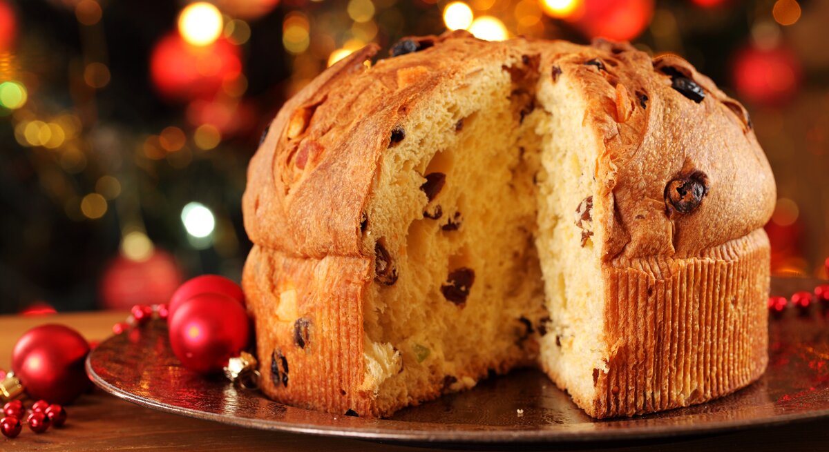 Angeschnittener Panettone vor weihnachtlichem Ambiente. 