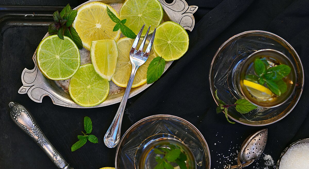 Limetten-Heißgetränk von oben aufgenommen neben Tablett mit Limettenscheiben. 