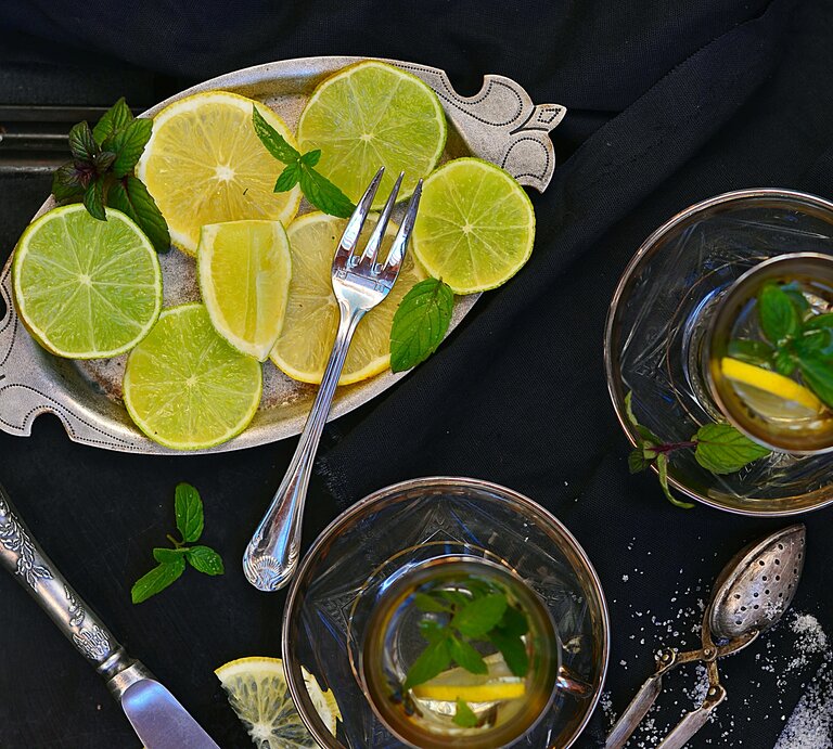 Limetten-Heißgetränk von oben aufgenommen neben Tablett mit Limettenscheiben.  | © GettyImages/Zoryana Ivchenko