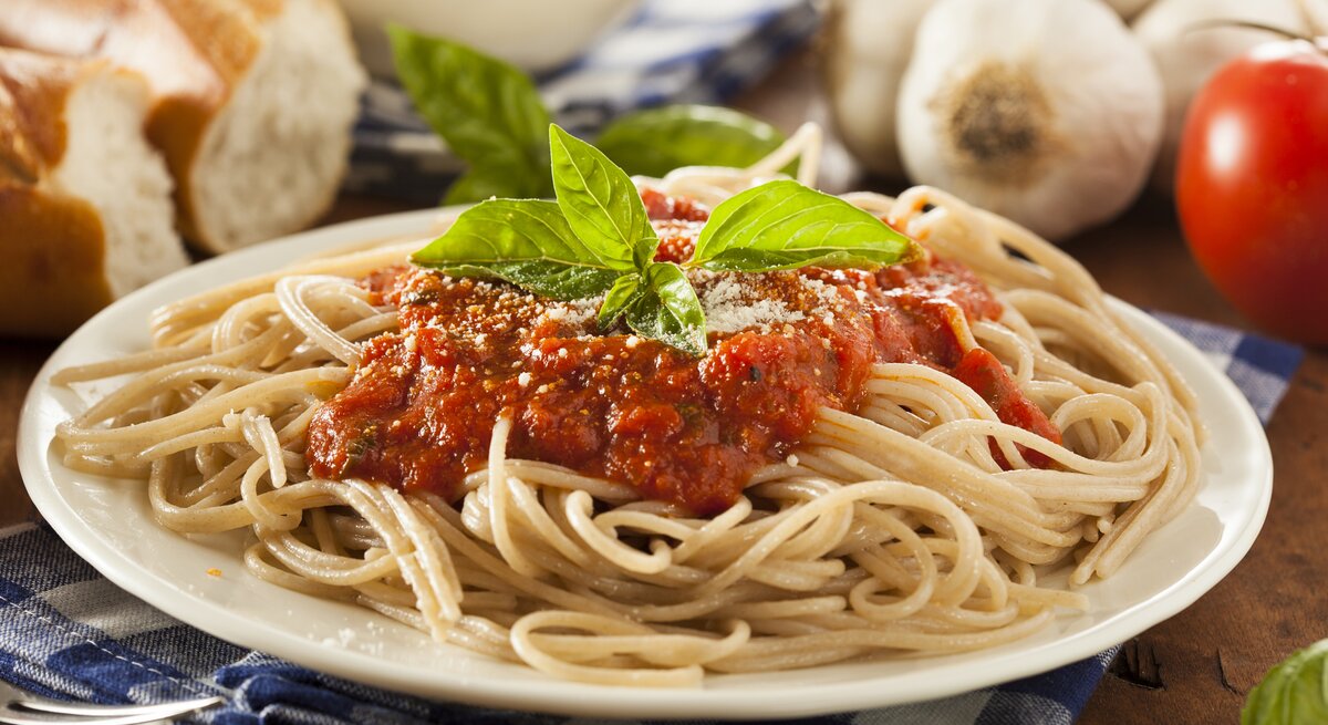 Ein weißer Teller, darauf eine Portion Spaghetti mit Tomatensoße. 