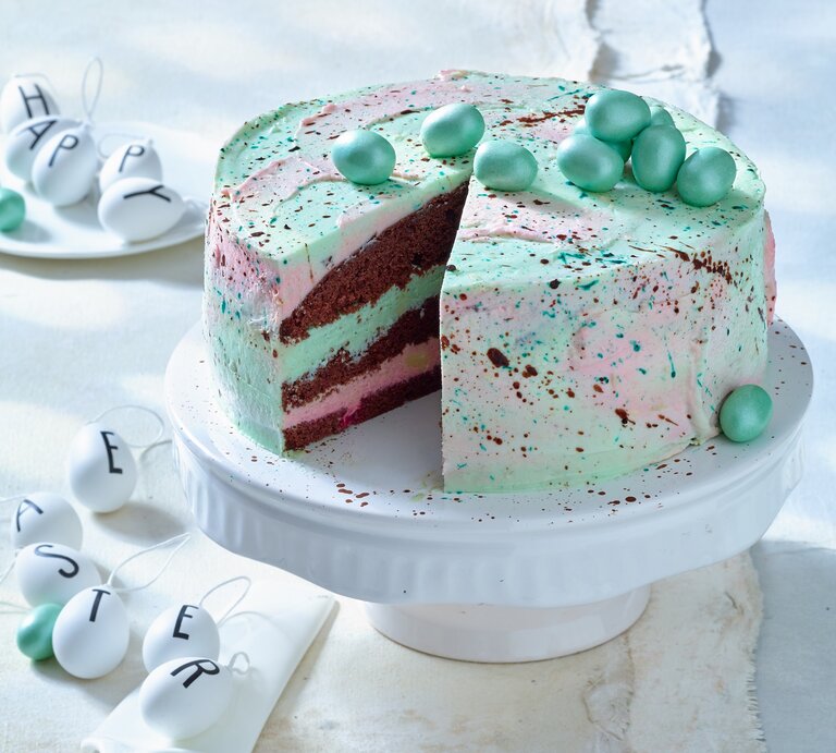 Waldmeister-Himbeer-Torte: Ostertorte mit grünlicher Creme und Schokoeiern auf einem weißen Servierteller. | © Matthias Liebich