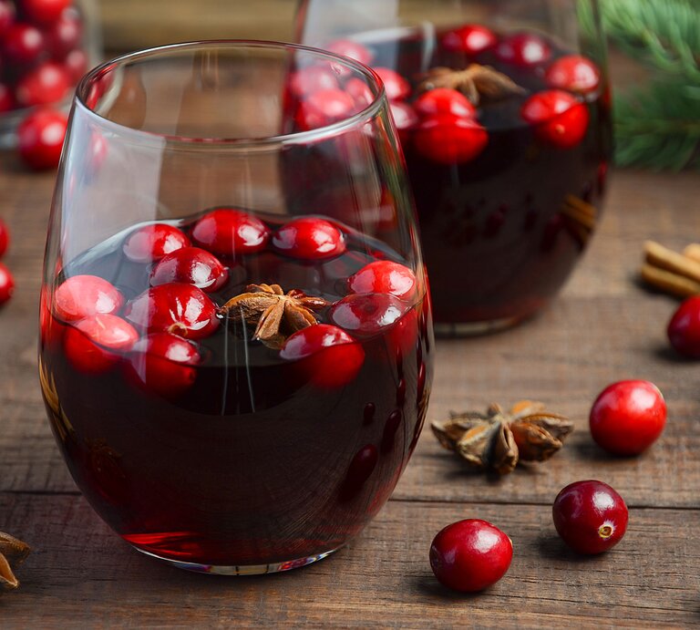 Ein Holztisch mit zwei Gläsern und Glühwein nah fotografiert. im Hintergrund Tannenzweige und Weihnachtsdeko. | © iStock/JulijaDmitrijeva