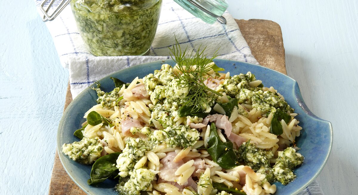 Feta-Dill-Pesto mit Orzo-Nudeln auf einem blauen Teller. 