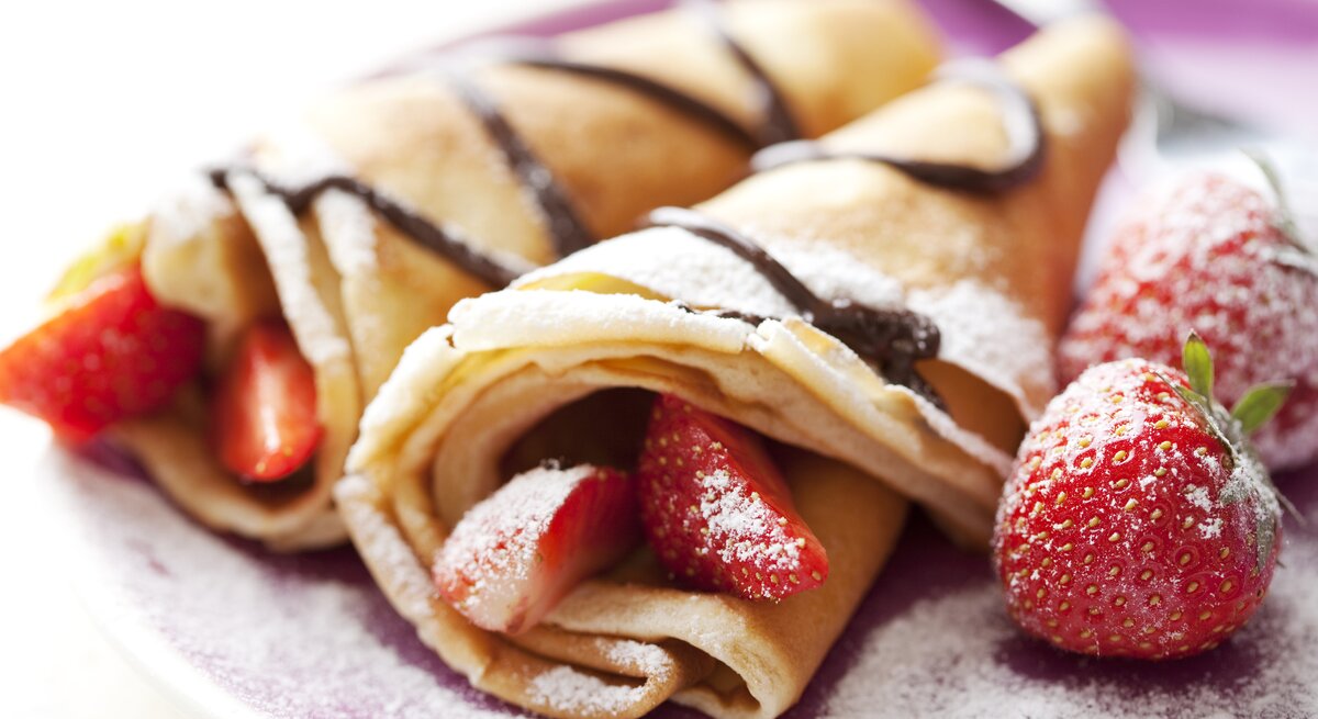 Seitliche Ansicht von Palatschinken mit Schokosoße und Erdbeeren.