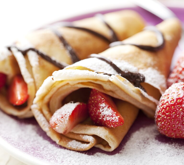 Seitliche Ansicht von Palatschinken mit Schokosoße und Erdbeeren. | © iStock/loooby