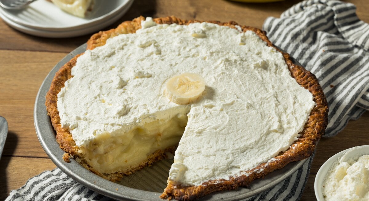 Pie mit bananen-Pudding-Füllung und Schlagsahne auf Holztisch. 