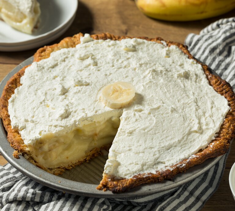 Pie mit bananen-Pudding-Füllung und Schlagsahne auf Holztisch.  | © Getty Images/ bhofack2