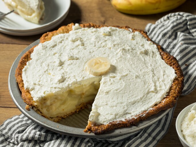 Pie mit bananen-Pudding-Füllung und Schlagsahne auf Holztisch.  | © Getty Images/ bhofack2