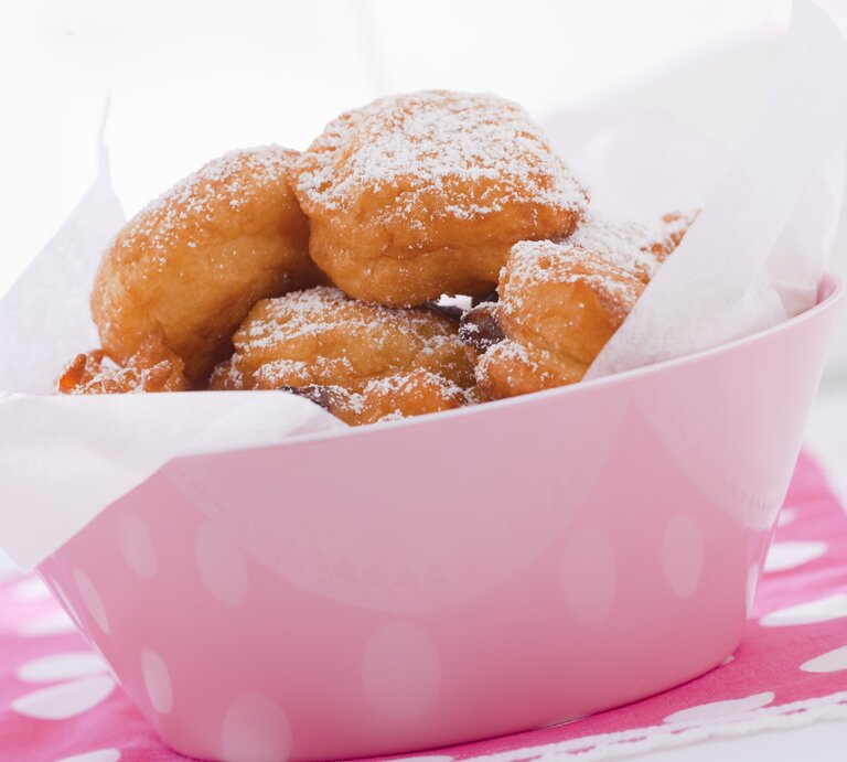 Mehrere Fritule in ein Papier gewickelt in einer ovalen Form aus Porzellan. | © StockFood / Studio Lipov