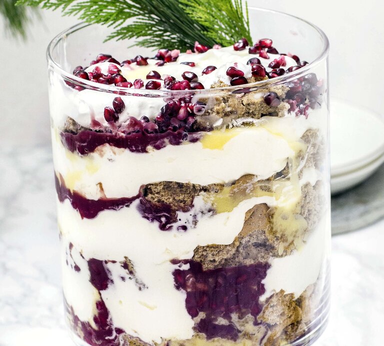 Das Lebkuchen-Trifle mit Eierlikör im Glas vor hellem Untergund mit weihnachtlicher Deko garniert. Alles sehr nah und direkt von vorne fotografiert. | © Stockfood/Picture Press/Jasmin Krause