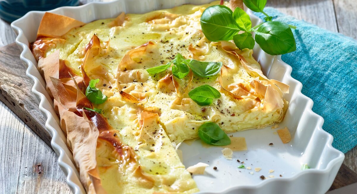 Ziegenkäse-Pie in einer viereckigen Auflaufform / Filoteig / frische Basilikumblätter / Untergrund Holz / 