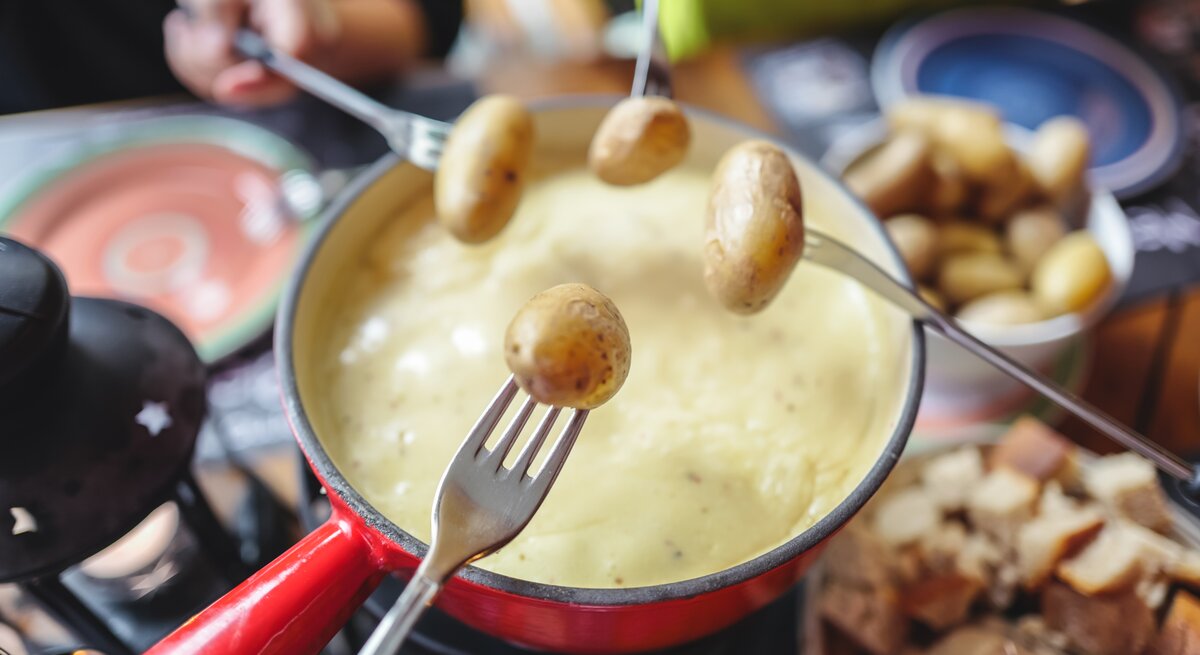 Kartoffeln werden in Käsefondue getaucht.