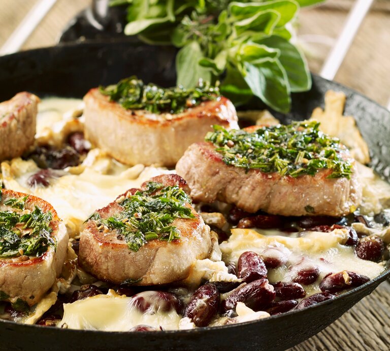 Schweinefilets mit Kräuterkruste auf Kidneybohnen mit Käse überbacken. Alles in der hohen Pfanne auf einem Holztisch fotografiert. | © StockFood/Studio R. Schmitz