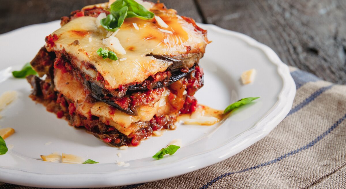 Parmigiana di Melanzane auf einem weißen Teller. 
