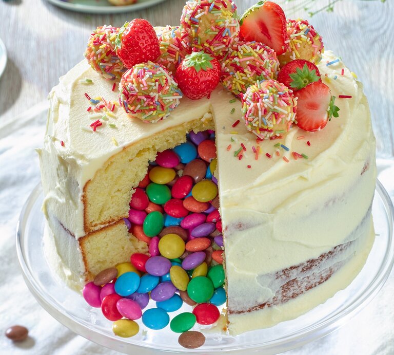 Piñata-Torte mit Erdbeeren auf einem Tortenteller vor weißem Hintergrund.  | © Matthias Liebich