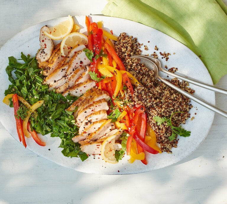 Quinoa-Hähnchen-Salat mit Rucola auf einem weißen Teller vor hellem Hintergrund, darauf ein grünes Tuch. | © MATTHIAS LIEBICH