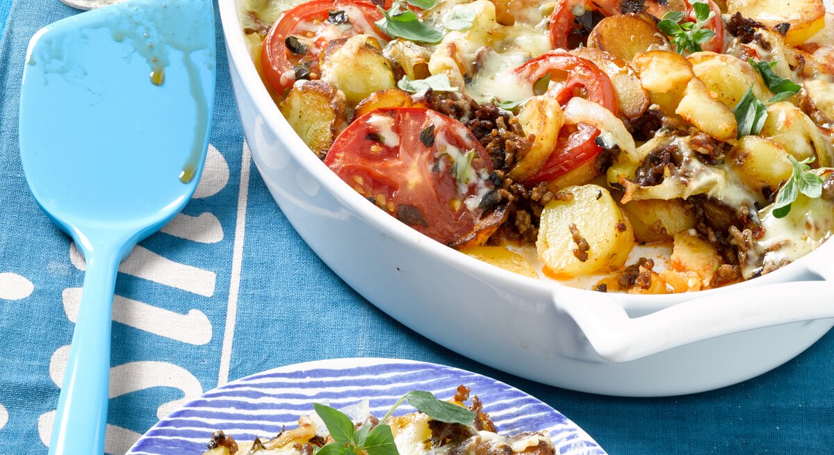 Bratkartoffel-Hack-Auflauf mit Tomaten und Gewürzen / Draufsicht schräg / Tellerrand / Kochlöffel