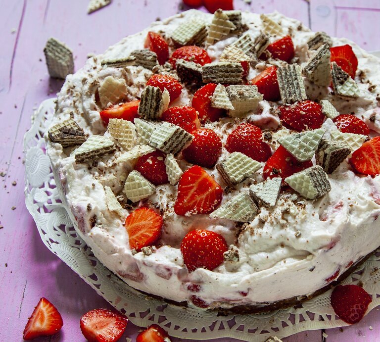 Die Erdbeer-Manner-Torte auf einem violetten Holztisch von schräg oben fotografiert. | © StockFood / Skowronek, Julia