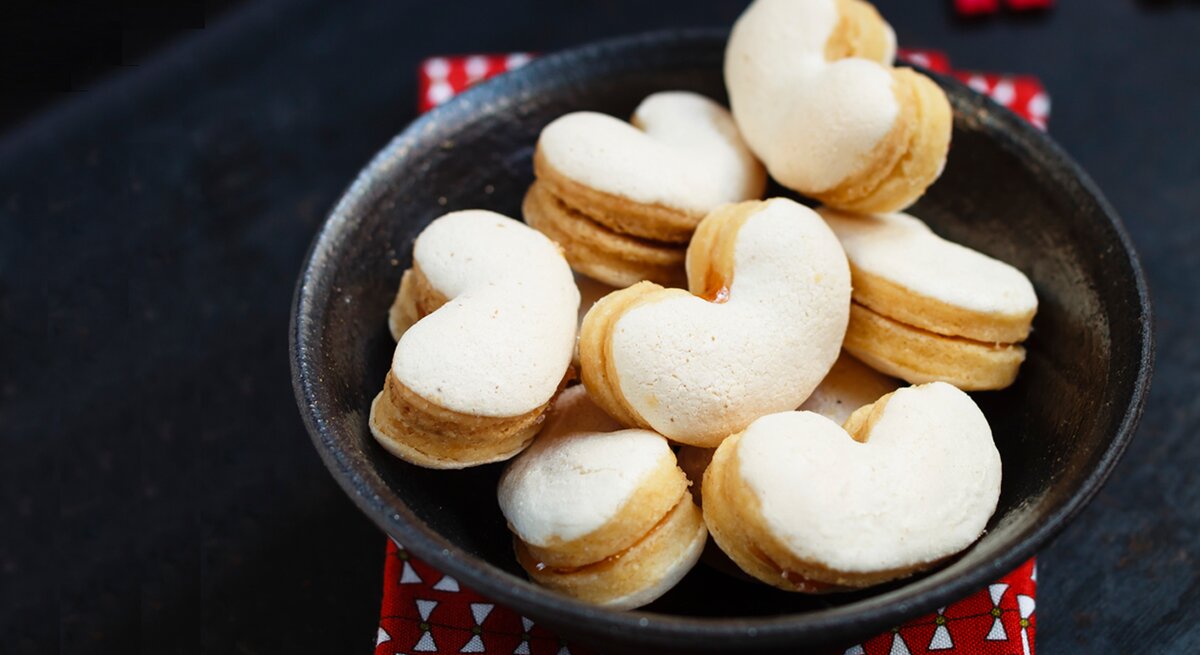 Herzförmige Baiser-Plätzchen in schwarzer Schale. 
