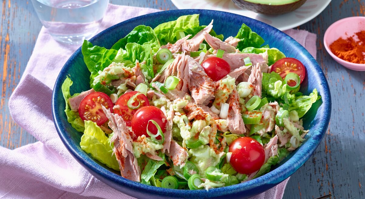Thunfisch-Avocado-Salat in runder Schüssel / Gabel / halbe Avocado mit Kern / Serviette aus Stoff