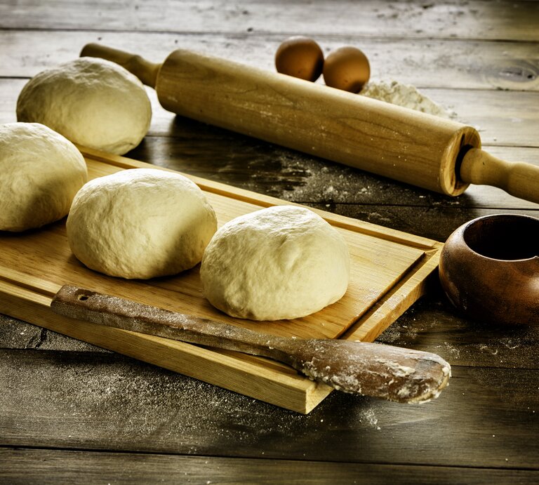 Mehrere Teigbälle auf Holzbrett.  | © iStock/ apomares