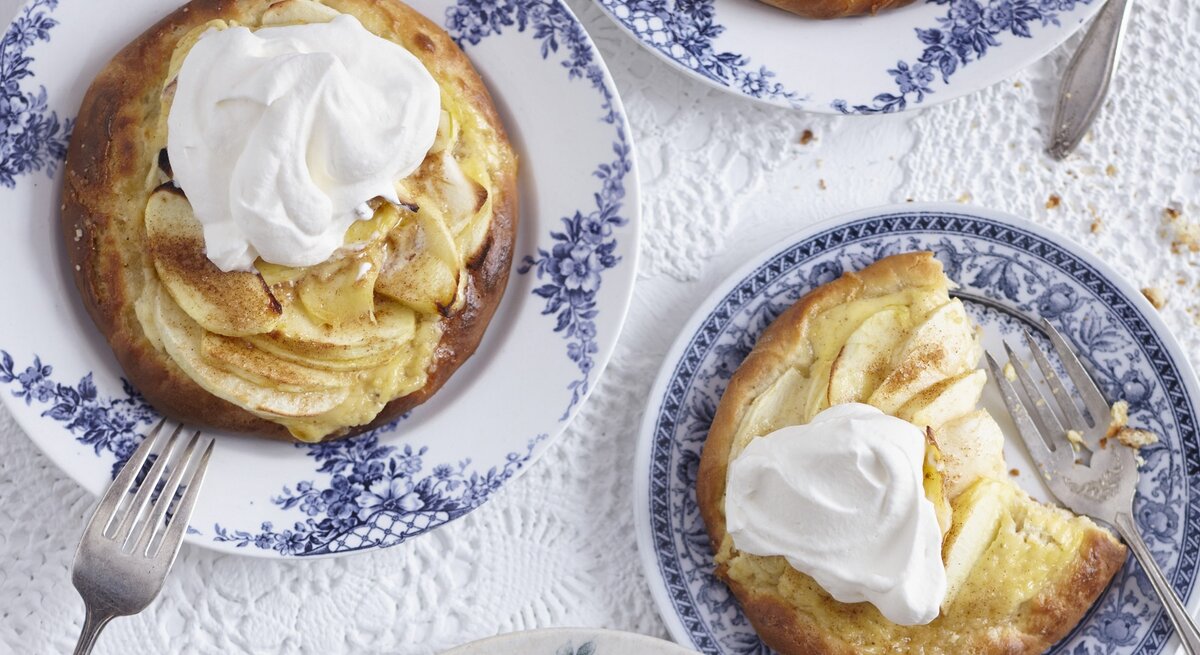 Die Apfel-Pizetten auf blau-weißen Tellern und weißer Tischdecke. Alles direkt von oben fotografiert.