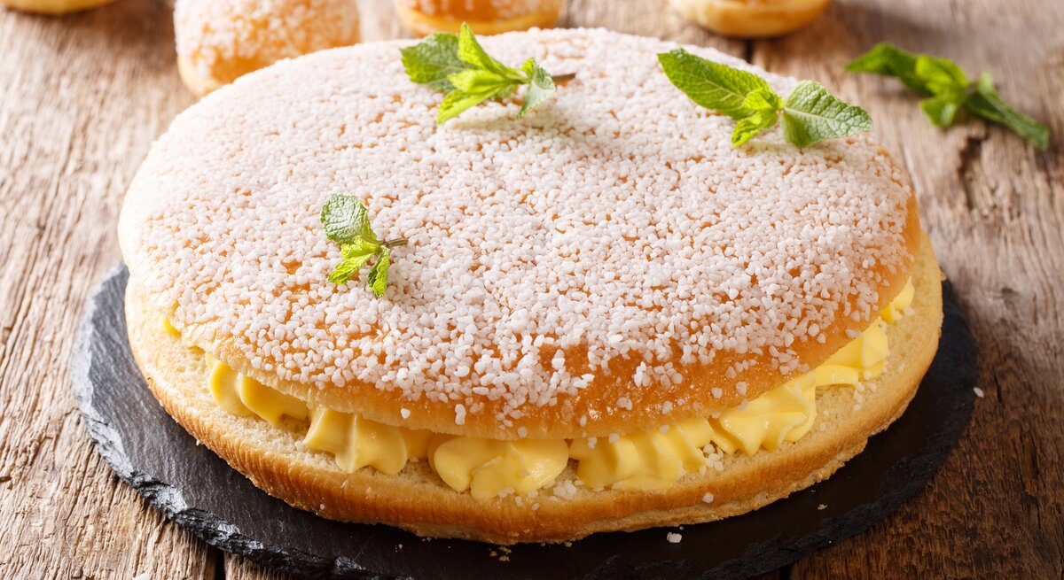 Kuchen mit Hagelzucker und Cremefüllung auf hölzernem Untergrund. 