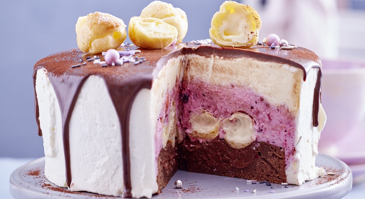 Die angeschnittene Torte auf einem grauen Kuchenständer mit unscharfem Hintergrund sehr nah fotografiert