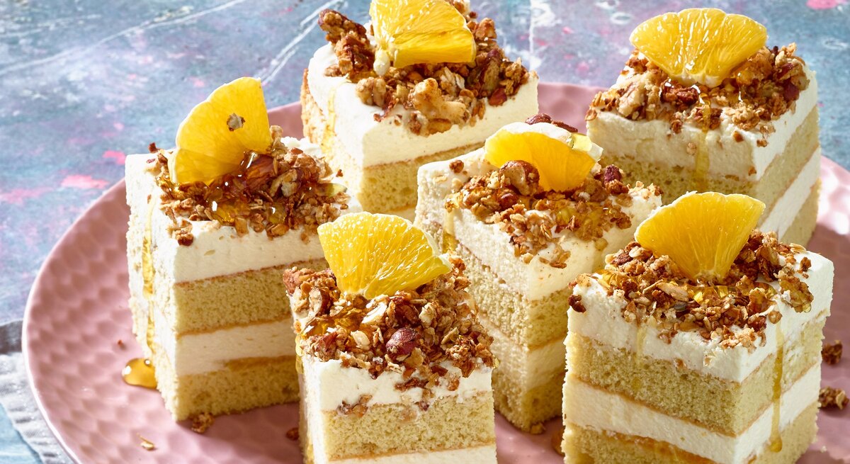 Orangen-Schmand-Kuchen auf einem rosa Teller. 